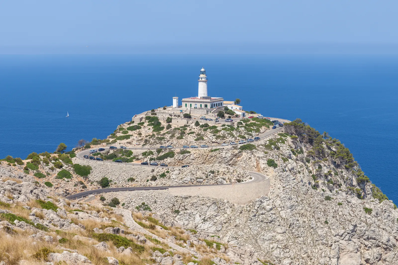 Witte vuurtoren op de rotsachtige kaap van Formentor met kronkelende weg en blauwe zee