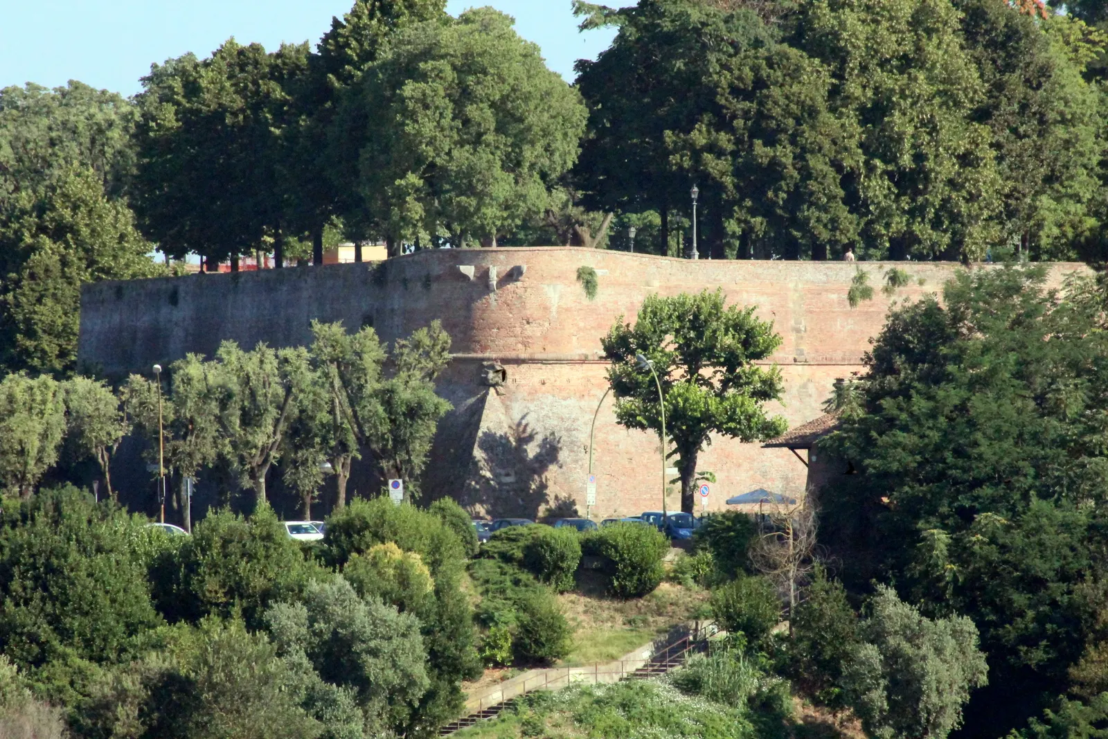 Massieve bakstenen vestingmuur van de Fortezza Medicea in Siena, omringd door groene bomen