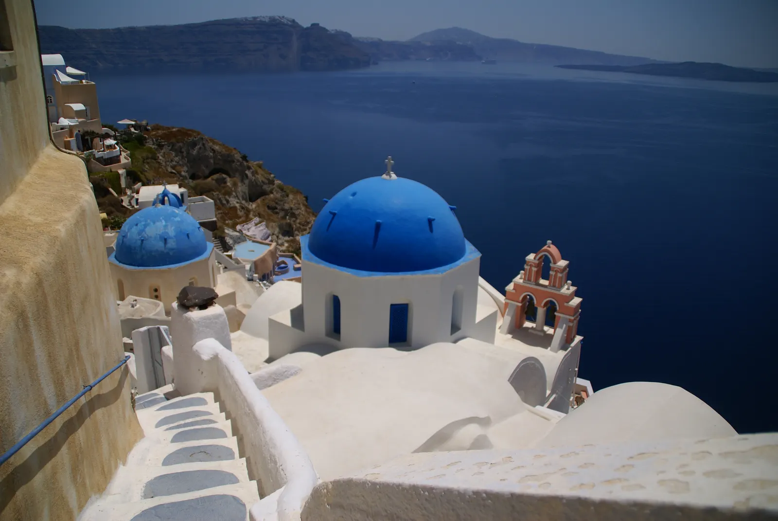 Witte huizen en blauwe koepelkerken van Oia op Santorini boven de diepblauwe caldera