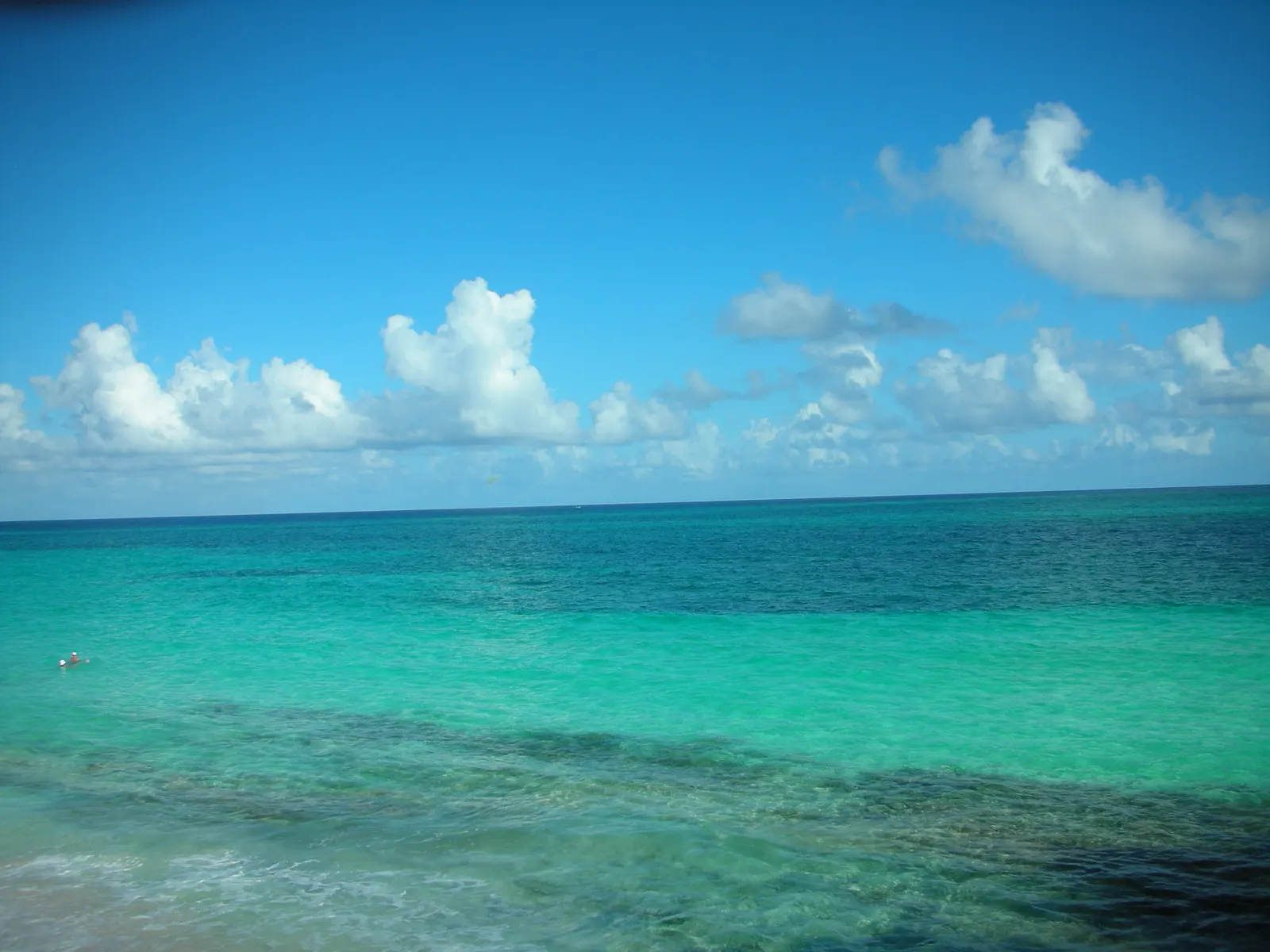 Turquoise zee met helder water en witte wolken aan de horizon bij Playa Santa Lucia