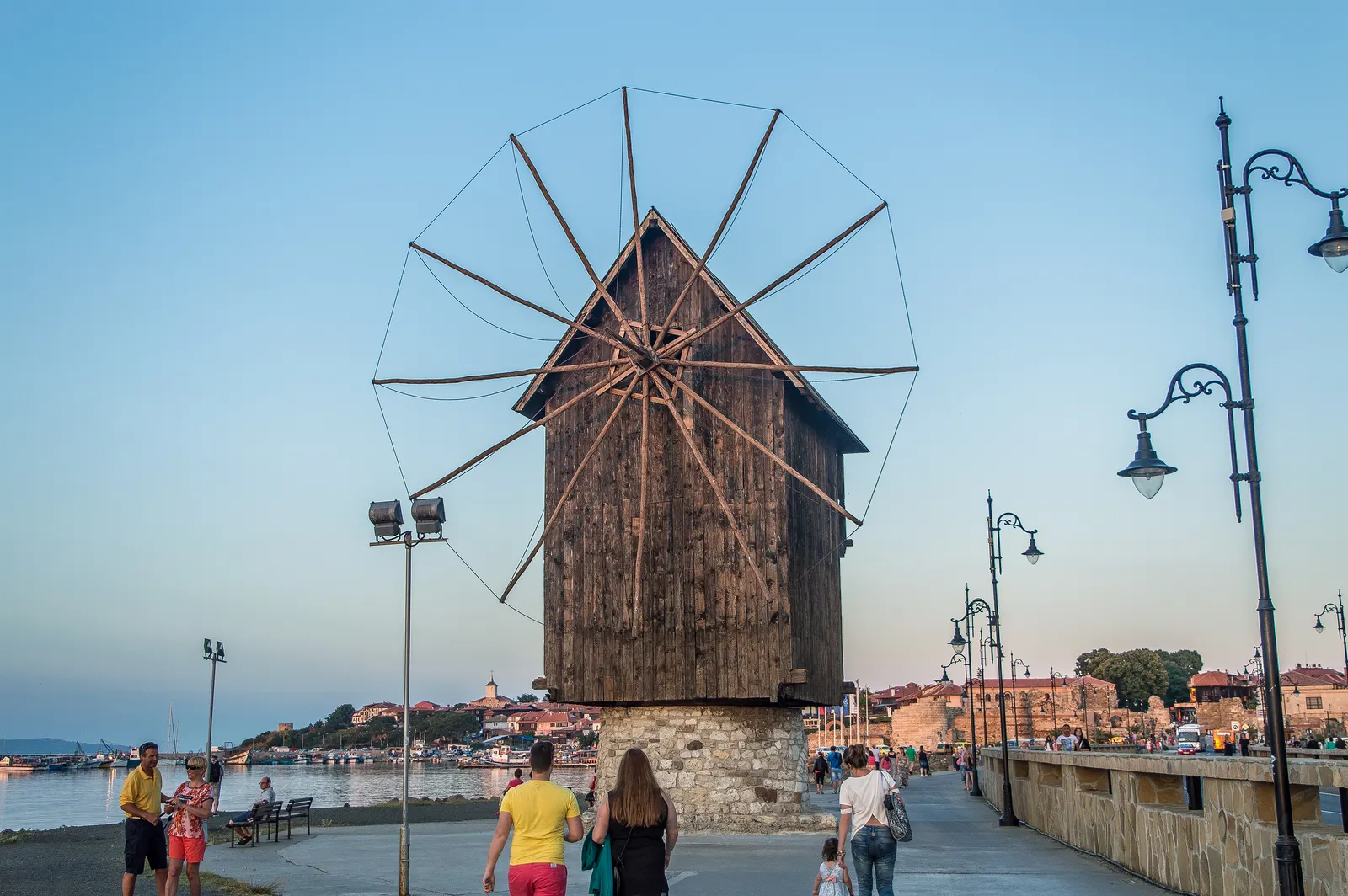 Oude houten windmolen op stenen voet aan de wandelboulevard naar het oude centrum van Nessebar bij zonsondergang