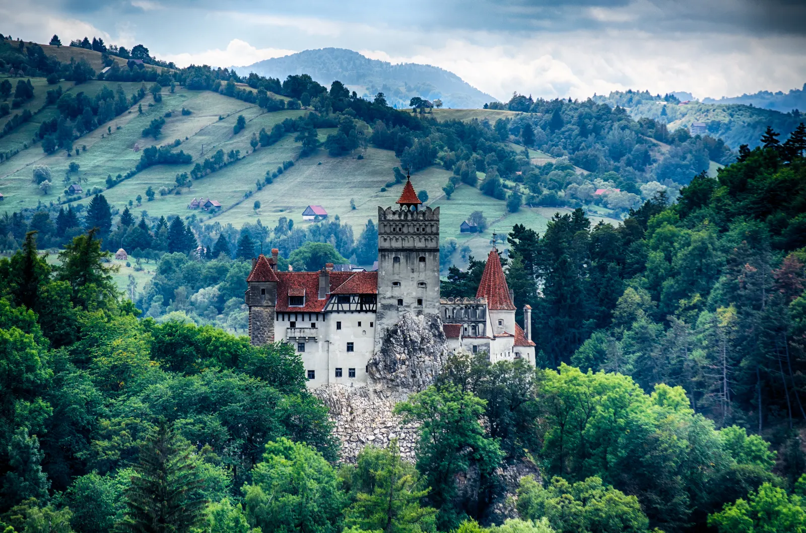 Kasteel Bran op een rots tussen beboste heuvels en groene weiden in Transsylvanië