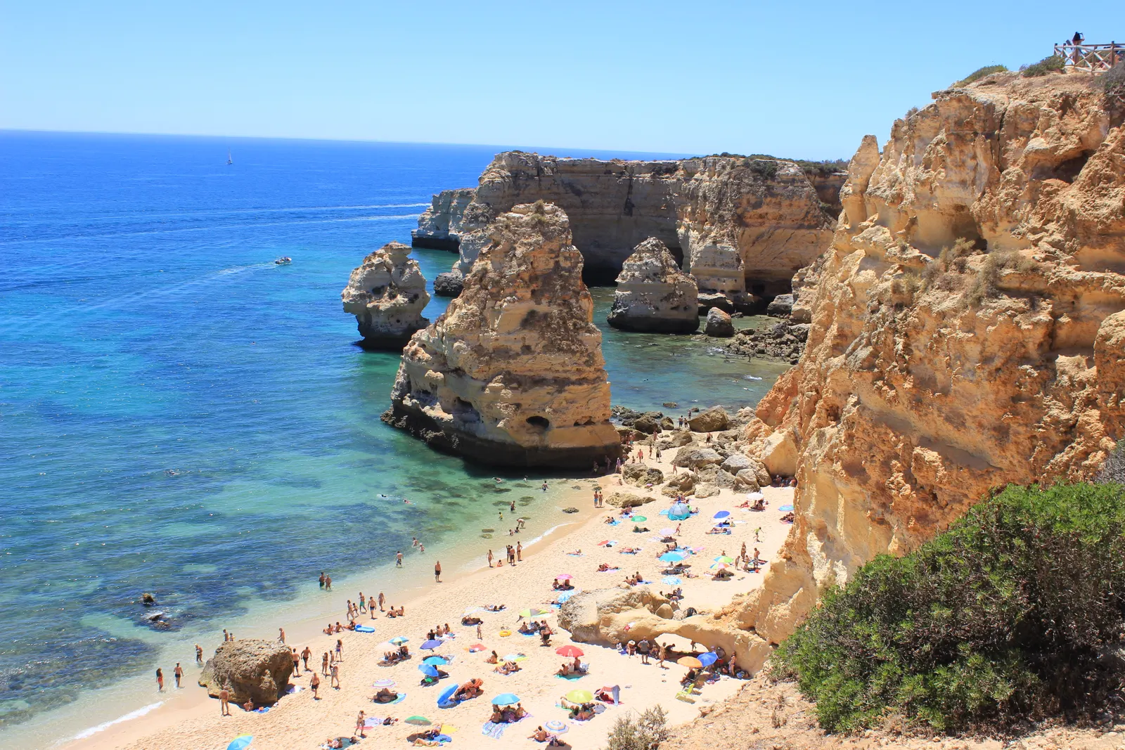 Zandstrand van Praia da Marinha met turquoise zee, rotspilaren en gele kliffen onder een blauwe lucht