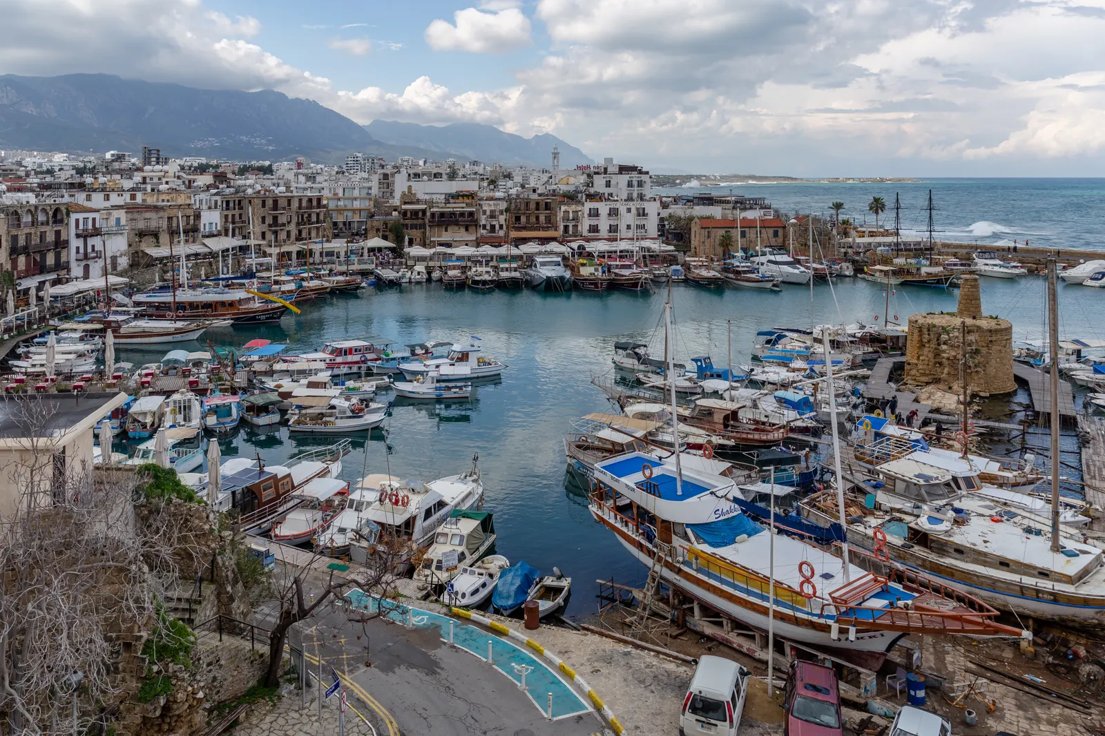 Uitzicht over de hoefijzervormige haven van Kyrenia met vissersboten, kades en bergen op de achtergrond