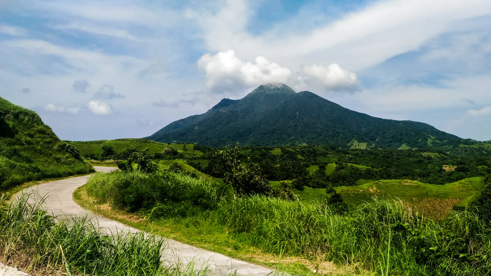 Kronkelende weg door groene heuvels richting de vulkaan Mount Iraya op Batan Island