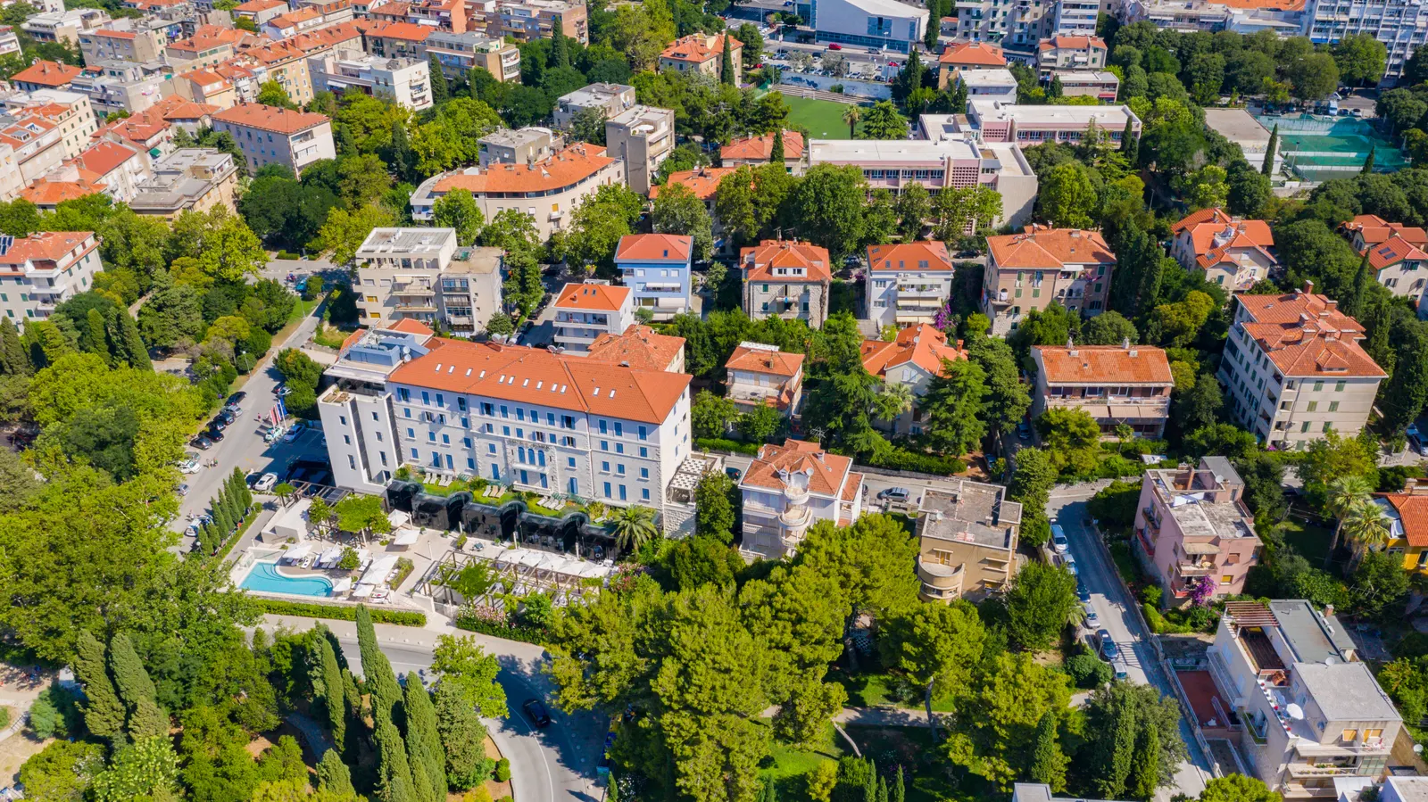 Luchtfoto van Hotel Park in Split met zwembad en tuin tussen groene bomen en villa's met rode daken