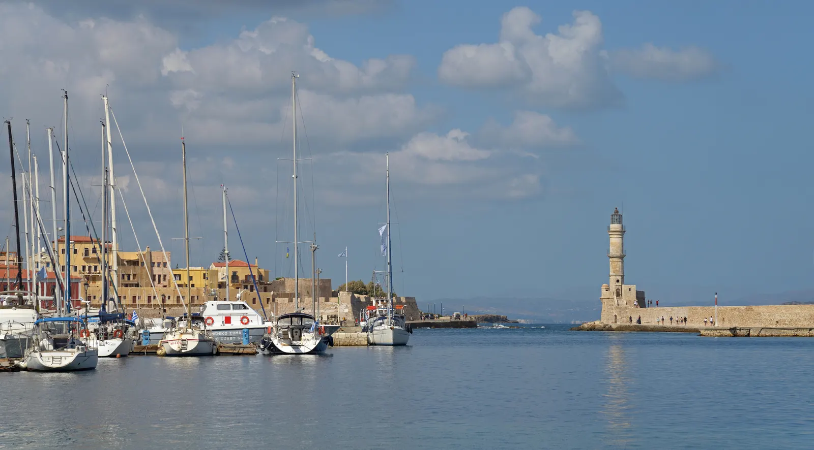 Zeilboten in de Venetiaanse haven van Chania met de oude vuurtoren en kleurrijke huizen onder een blauwe lucht