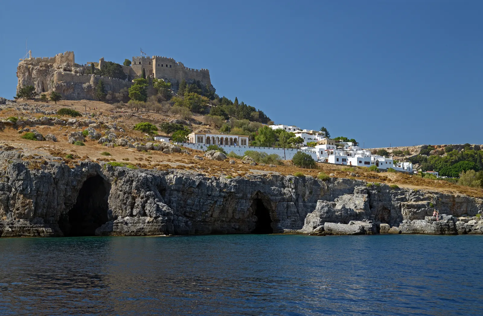 De akropolis van Lindos op een rots boven de zee, met witte huisjes en kliffen met grotten op Rhodos