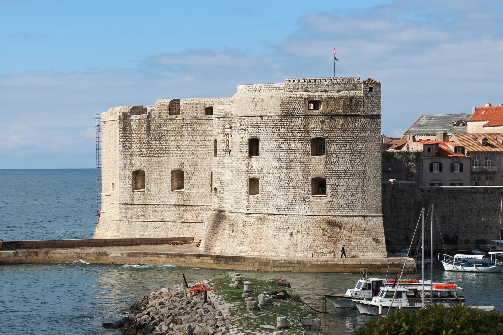 Fort Sint-Jan met ronde stenen toren aan de oude haven van Dubrovnik, met bootjes op het water