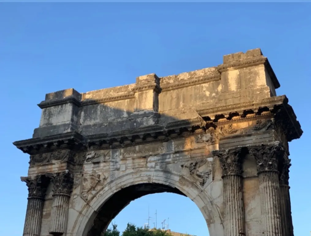 Bovenste deel van de Romeinse Triomfboog van de Sergii in Pula met Korinthische zuilen tegen een blauwe lucht