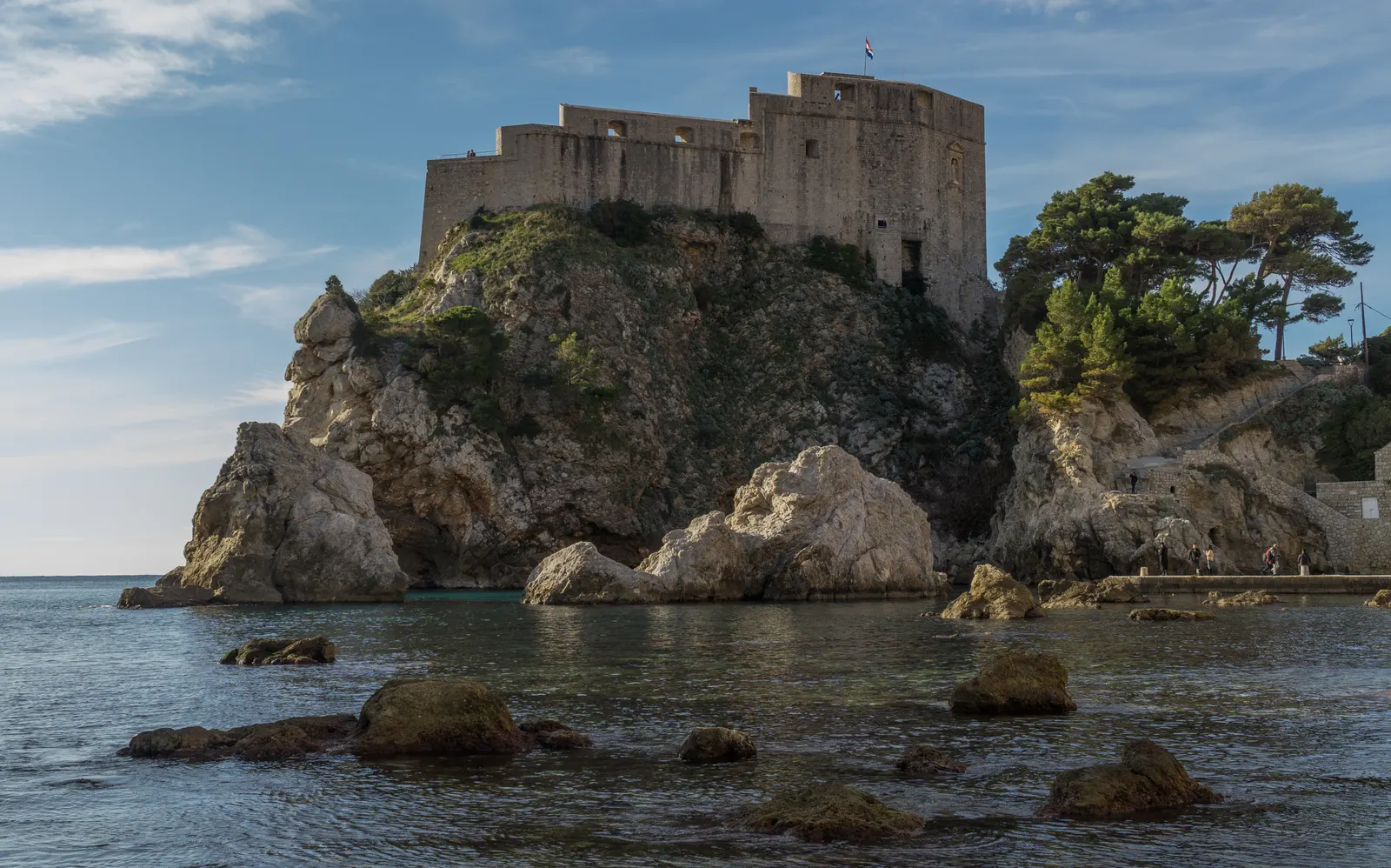 Fort Lovrijenac hoog op een rots boven de zee bij Dubrovnik, met rotsen in het water op de voorgrond